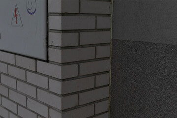 Brick corner with notice panel, quiet utilitarian interior scene showing closeup masonry texture,...