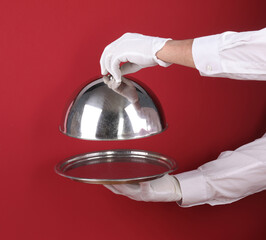 Waiter's hand with a tray isolated on a red background
