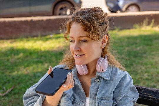 Woman with headphones using smartphone for voice command