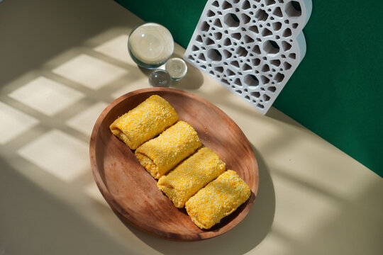 Risol Pastry Cake served on a Wooden Plate with Islamic Curved Decoration and a Green Background