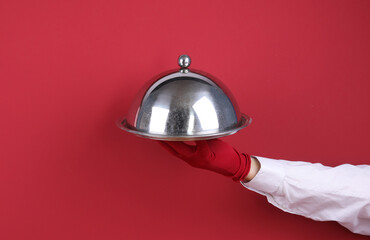 Waiter's hand with a tray isolated on a red background