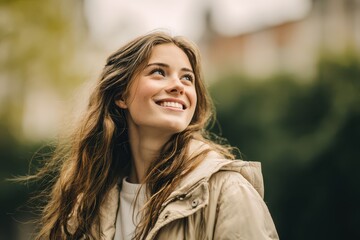 Obraz premium Candid outdoor portrait of a youthful woman in a winter coat smiling and looking up at the sky