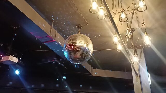 Silver mirror disco ball in the rays of the spotlights