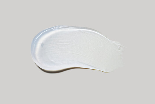 Cosmetic gel emulsion or serum vaseline mask with luminizer effect brush stroke smudge isolated on neutral grey background