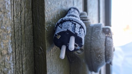 Frozen electrical plug and outlet on a cold winter day in a remote area