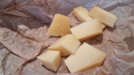 Cheese pieces on paper wrap at a kitchen table after cutting