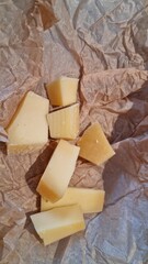 Different pieces of cheese on crumpled brown paper in a kitchen