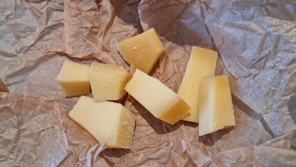 Cheese pieces placed on crumpled brown paper in a kitchen setting