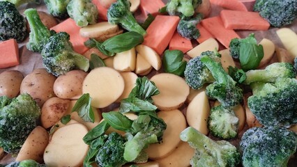 Fresh vegetables prepared for cooking on a baking sheet with herbs