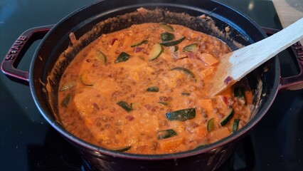 Cooking lentil stew with vegetables in a pot on the stove