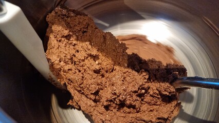 Mixing chocolate dough in a metal bowl with a stand mixer