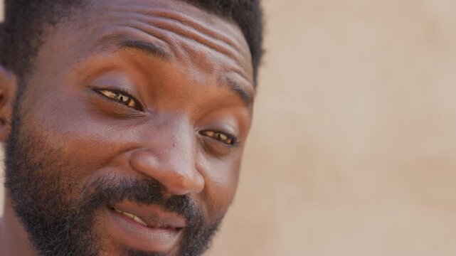 Man close up smiling with beard, warm sunlight on skin and neutral background. Thoughtful gaze suggests mentor or neighbor sharing candid story gentle expression, textured beard, subtle laugh lines