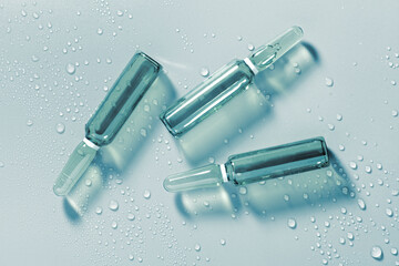 Blue glass ampoule injection or serum moisturizer booster on wet surface. Beauty product sample swatch. 