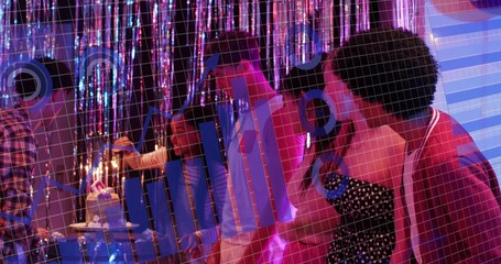 Leaning group of seven adults adjusting lit birthday candles at club-like lounge, polka-dot dress