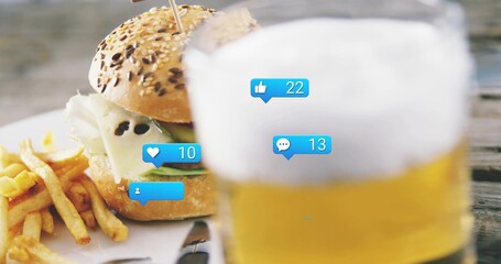 Showing seeded bun burger sitting with melted cheese, lettuce at pub table, fries, beer, blue icons