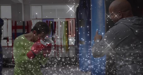 Holding red boxing gloves, boxer training in gym, coach wearing grey hoodie holding pad © vectorfusionart