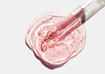 Liquid pink red orange oil or serum on neutral gray isolated background. Beauty product sample...