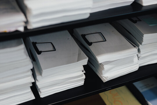 A cabinet in an office with documents in piles.