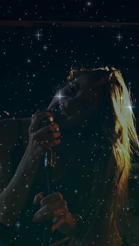 Vertical video: Lead singer gripping mic singing leaning flipping hair starry overlay over her