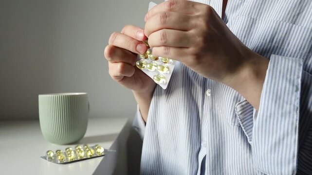 Woman taking fish oil omega 3 capsules for woman health. Supplements and vitamins, self treatment, biohacking.