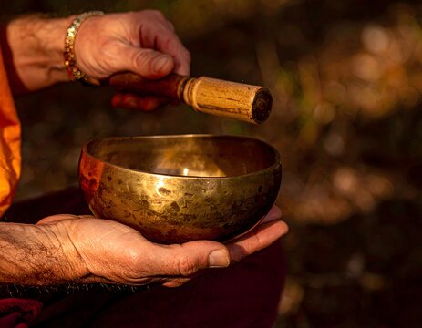 Monje tocando cuenco tibetano en ritual de meditaci&oacute;n al aire libre