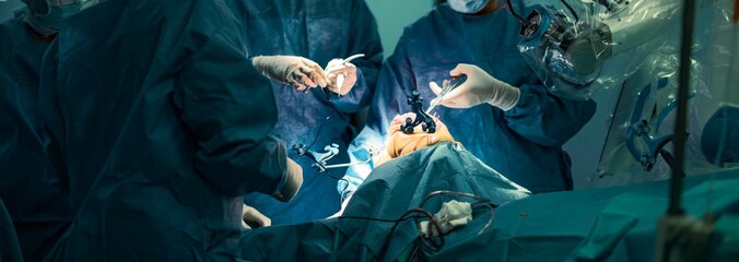 Surgeons, dressed in blue sterile gowns, perform a knee replacement using a robotic-assisted system, showcasing precision and teamwork in a modern operating room filled with advanced technology