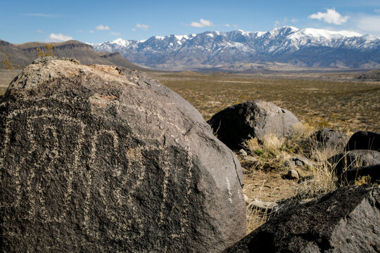 Southeast New Mexico. Ancient Native American petroglyphs on a rock with mountain range in the background. 