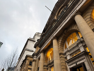 Naklejka premium Historic Manchester building with grand columns and warm illuminated arches at dusk UK