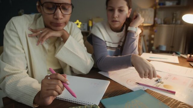 Young math tutor communicating with teen girl and using calculator while they having personal lesson at home