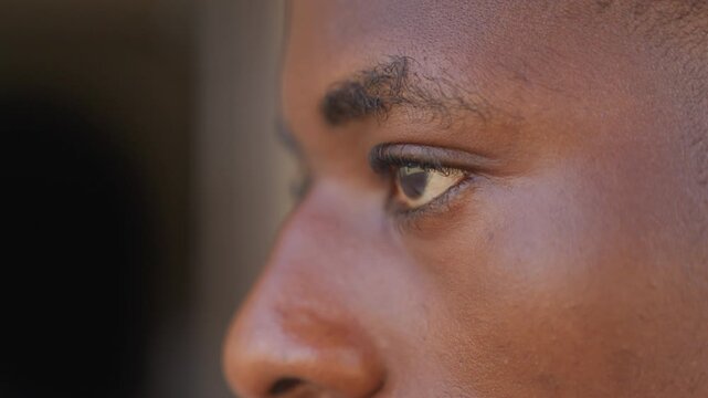 Closeup profile black athlete focusing, young sprinter locked in gaze, side portrait showing skin texture and eyebrow detail, quiet pregame concentration, cinematic shallow depth