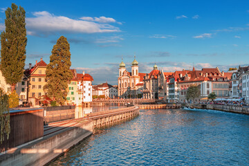 Fototapeta premium Beautiful view of Lucerne, Switzerland featuring the famous wooden Chapel Bridge with Water Tower over the Reuss River. Scenic cityscape with alpine mountains, clear water, and colorful historic archi