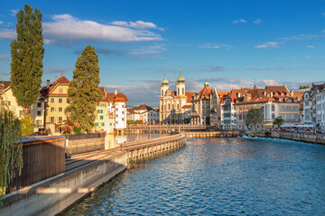 Obraz premium Beautiful view of Lucerne, Switzerland featuring the famous wooden Chapel Bridge with Water Tower over the Reuss River. Scenic cityscape with alpine mountains, clear water, and colorful historic archi