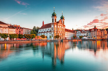 Obraz premium Beautiful view of Lucerne, Switzerland featuring the famous wooden Chapel Bridge with Water Tower over the Reuss River. Scenic cityscape with alpine mountains, clear water, and colorful historic archi