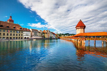 Obraz premium Beautiful view of Lucerne, Switzerland featuring the famous wooden Chapel Bridge with Water Tower over the Reuss River. Scenic cityscape with alpine mountains, clear water, and colorful historic archi