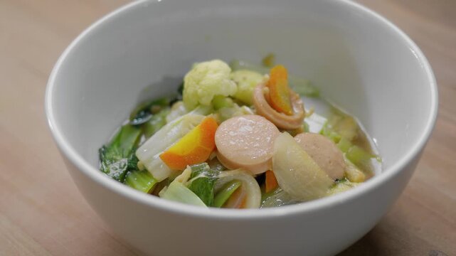 Close up view of freshly cooked chinese cuisine capcay or chop suey in a white ceramic bowl on a wooden table