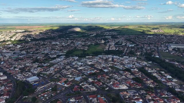 Aerial video footage of a bustling city with a mountain range in the background under a blue sky