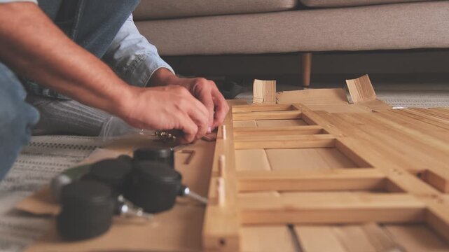 Unrecognizable person assembling flat-pack furniture at home following the instructions