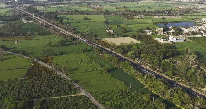 Aerial view of indian railway train passing through the rural village in haryana
