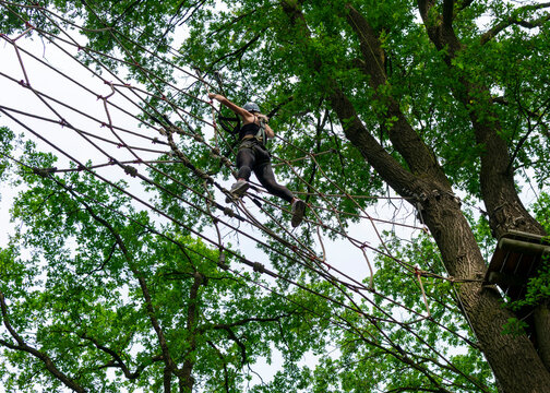 Young girl progressing through forest climbing course