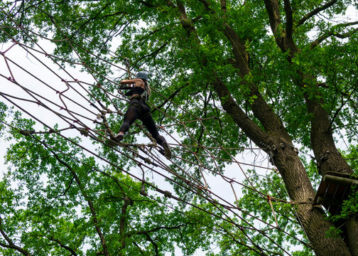 Active girl climbing in high ropes course in forest