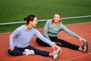 Two women stretching together and smiling during outdoor training