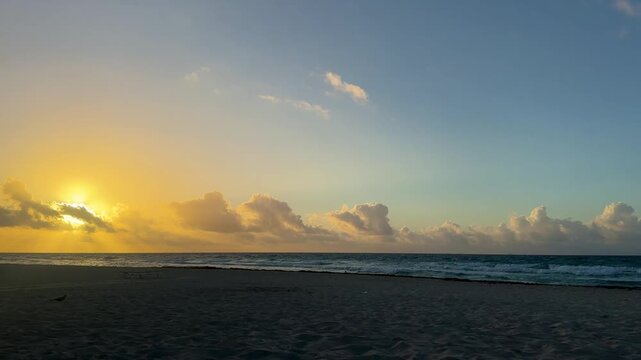 Golden Sunrise Over Ocean with Clouds and Sandy Beach
