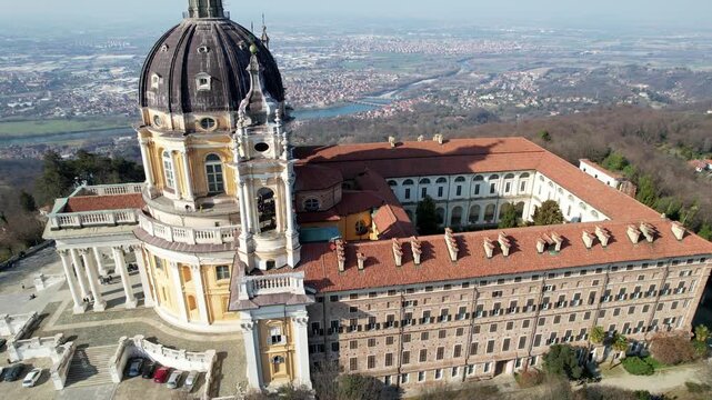 Aerial drone view of the majestic Basilica of Superga and its monastery buildings on the hilltop in Turin, Italy, historic baroque architecture, city panorama, sunny daylight.