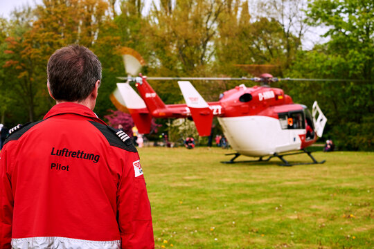 GREIFSWALD, MECKLENBURG-VORPOMMERN, GERMANY - May 13, 2017: Air Rescue Pilot Stands Before a Medical Helicopter on a Grassy Field