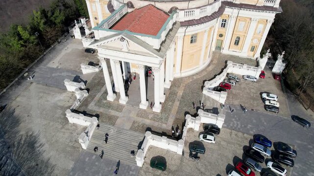 Aerial top view of the Basilica of Superga portico and entrance with tourists and cars in Turin, Italy, baroque architecture, historic hilltop landmark, sunny daylight.