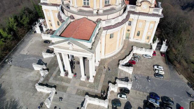 High angle drone shot reveals the majestic Basilica of Superga with its classical portico and surrounding city blocks in Turin, Italy, urban architecture, aerial heritage panorama.