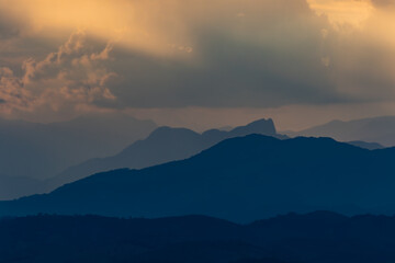Obraz premium Sunset Light Casting Over Layered Mountain Peaks