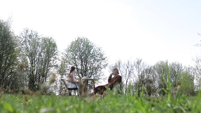 A loving couple is having breakfast at a table in the garden in spring