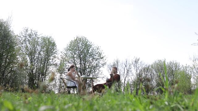 A loving couple is having breakfast at a table in the garden in spring