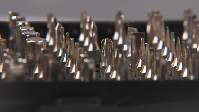Close up of small screw driver and screw bolt bit set for a screwdriver on electronic electronics devices like boards, circuits, and repair jobs in slow motion and blurry defocused background plate